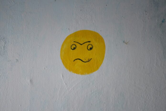 Photo by Orkun Azap a yellow smiley face painted on a white wall