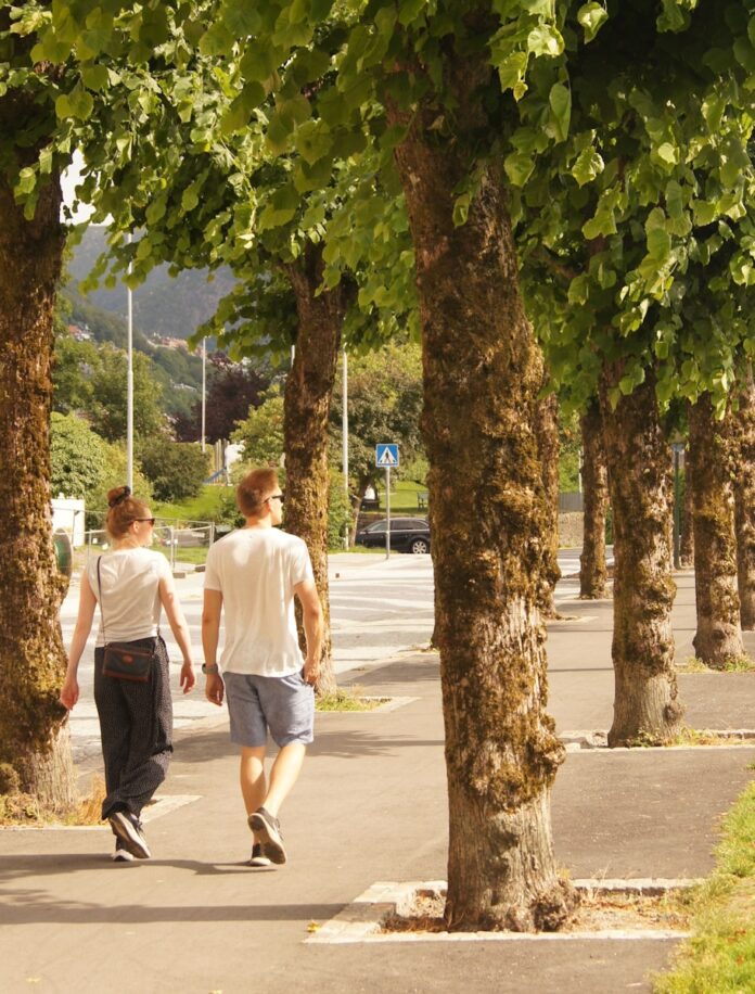 man in white t-shirt walking on sidewalk during daytime