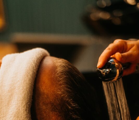 “두피부터 건강하게, 요즘 뜨는 헤어케어 루틴” a man getting his hair washed in a sink