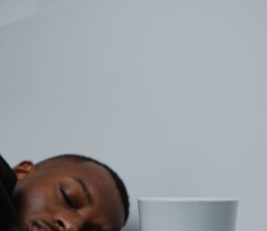 잠들기 전 루틴이 바뀐다…수면 건강 지키는 신(新) 트렌드와 실천법 a man sleeping on top of a stack of books next to a cup of coffee