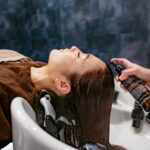 “내 머리결, 내가 지킨다”… 건강한 헤어 케어, 일상에서 시작하세요 a woman getting her hair washed in a sink