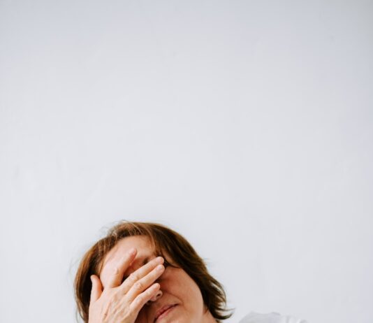 “만성피로, 단순 피로 넘어 ‘현대인의 질환’으로… 맞춤형 관리가 핵심” a woman sitting on a couch holding her hands to her face