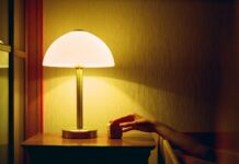 집에서 쉽게 실천하는 ‘스마트한 수면 루틴’이 주목받는다 a person's hand on a table next to a lamp